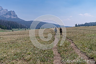 Two male hikers wearing large backpacks hike along the Upper Brooks Lake trail on a hazy day Editorial Stock Photo