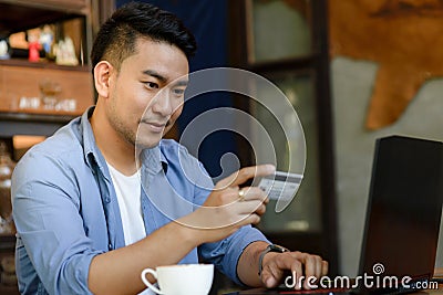 & x22; Making online bank transfer, man holds a credit card while ent Stock Photo