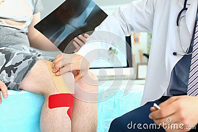 X-ray image of knee injury patient with kinesio tape on knee at orthopedist appointment Stock Photo