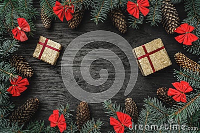 Xmas greeting card. Fir branches with cones and red bowls, on black wood background. Christmas presents Stock Photo