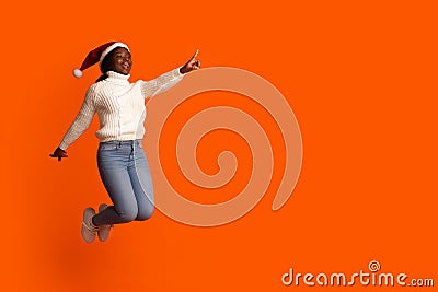 Xmas Offer. Joyful Black Santa Lady Jumping And Pointing At Copy Space Stock Photo