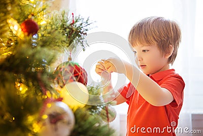 Xmas party celebration. Child decorating Christmas tree at home. Family with kids celebrate winter holidays. New year small boy at Stock Photo