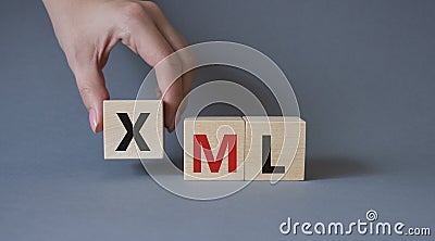 XML - Extensible Markup Language. Wooden cubes with word XML. Businessman hand. Beautiful grey background. Business and Extensible Stock Photo