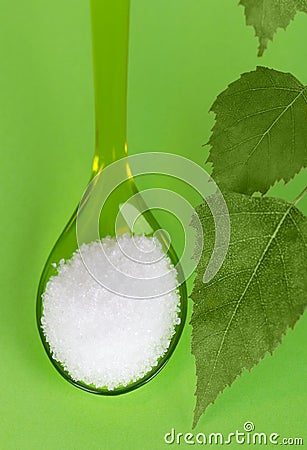 Xylitol birch sugar on plastic spoon over green Stock Photo