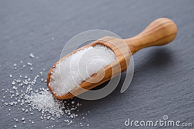 Xylitol or birch sugar in a wooden scoop on black background, selective focus Stock Photo