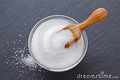 Xylitol or birch sugar in a wooden scoop and glass bowl on black background, selective focus Stock Photo