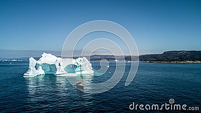 Yacht and amazing iceberg. Greenland view from drone. Stock Photo