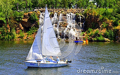 The yacht and boat sail near a beautiful waterfall on the Dnieper river, landscape. Summer recreation and water sports in the Editorial Stock Photo