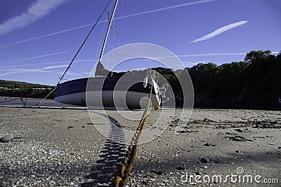 Yacht boat on a sandy beach tethered with a rusty chain Stock Photo