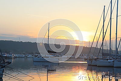 The yacht returns from the voyage to the marina during the morning dawn sailing past the moored sailing yachts. Marine life style. Stock Photo