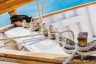 Classical wooden sailing boat deck with tied nautical ropes on wood cleats Stock Photo