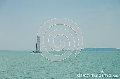 Yachting, luxury, sailing, cruise concept. A sailboat is waiting in day stillness under beautiful blue sky with clouds on Lake Bal Stock Photo