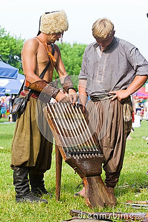 Zaporozhian Sich cossack and his squire load mouth of ancient machine gun with bullets and gunpowder Editorial Stock Photo