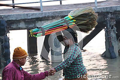 Myanmese woman with thanakha Myanmar powder on her face put the broom on her head and the man hand in hand to get up of the boat Editorial Stock Photo