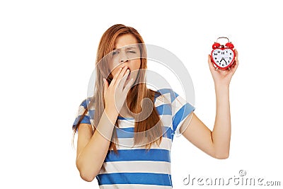 Yawning teenage woman holding alarm clock Stock Photo