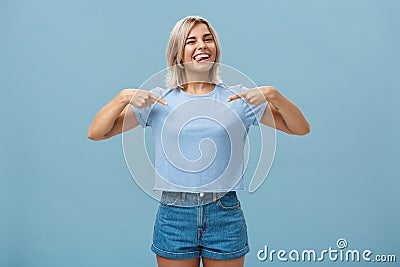 Yeah proud of myself. Self-assured joyful and carefree attractive blonde female with tanned skin and tattoos pointing at Stock Photo