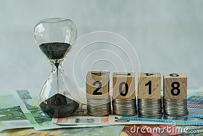 Year 2018 business time countdown or long term investment concept as hourglass or sandglass on pile of Euro banknotes with wooden Stock Photo