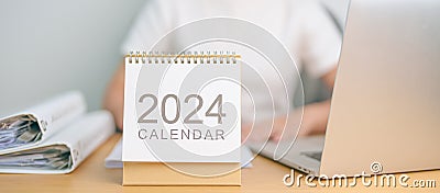 2024 Year Calendar on table with business woman using laptop computer. countdown, Happy New Year, Resolution, Goals, Plan, Action Stock Photo