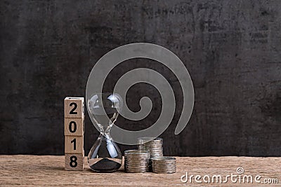 Year 2018 financial or investment time or goals concept with hourglass or sandglass and stack of coins and cube block with number Stock Photo