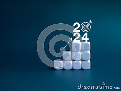 2024 year number with target icon and rise up arrow on white blocks as a graph steps on blue background. Stock Photo