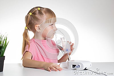 A 5-year-old caucasian girl is breathing into an inhaler at home. Treatment of cough and lung diseases in children, dilution of Stock Photo