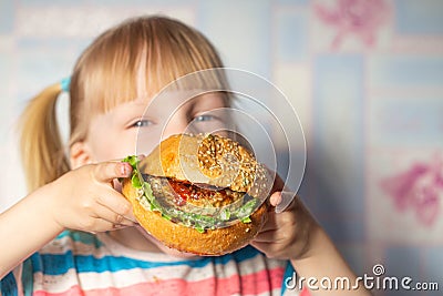 4 year old caucasian girl eating a big hamburger cooked at home. Copy space for text Stock Photo
