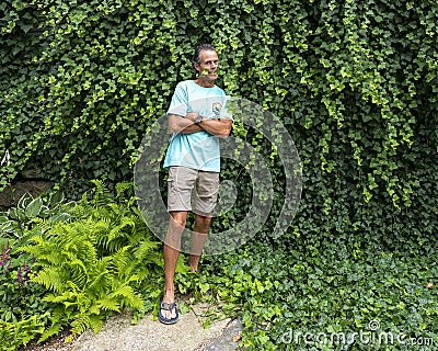52 year-old Caucasian male posing in front of a dense wall of green ivy in Bar Harbor, Maine. Stock Photo