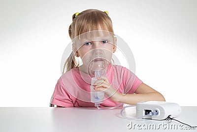 A 5-year-old caucasian girl is breathing into an inhaler at home. Treatment of cough and lung diseases in children, dilution of Stock Photo