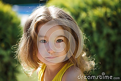 A 3-year-old girl with long, lush blond hair looks into the frame. Stock Photo