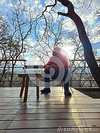 40-year-old Latino man drinks wine on the terrace of his cabin in the woods relaxes in his free time on weekend vacations Stock Photo
