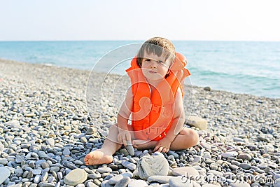 2 years child in life-saving jacket sitting on the seaside Stock Photo