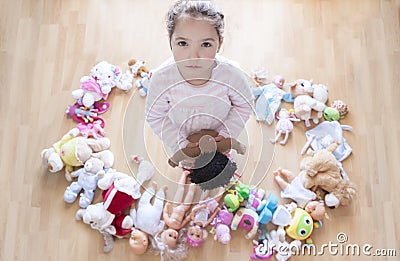 5 years little girl unhappy with lots of toys. Too many toys concept at Infant Behaviour Stock Photo