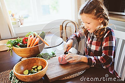 8 years old child girl help mom to cook vegetable salad at home Stock Photo