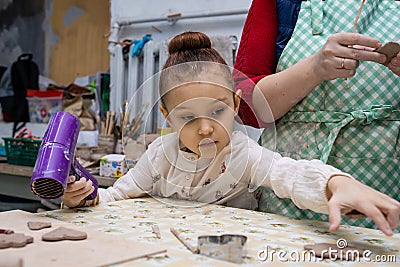 Child girl with a teacher in a pottery workshop. Stock Photo