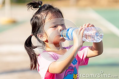 A 3-4 years old girl was drinking water to quench her thirst due to the hot weather. Kid sweat on their faces. Stock Photo