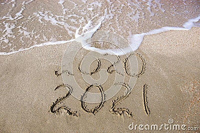 2020, 2021 years written on sandy beach sea. Wave washes away 2020 Stock Photo