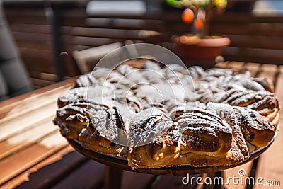 Yeast braid in the sun designed like a flower or star on a wooden plate with a tree and easter eggs in the background Stock Photo