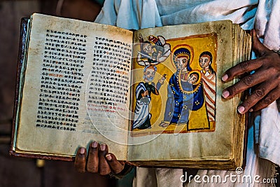 Yeha, Ethiopia - Feb 10, 2020: an orthodox priest shows a painted holy bible in the Great Temple of the Moon Editorial Stock Photo