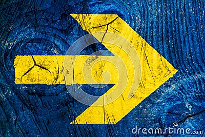 Yellow arrow direction sign over vivid bright blue color wooden wall with imperfections and cracks Stock Photo