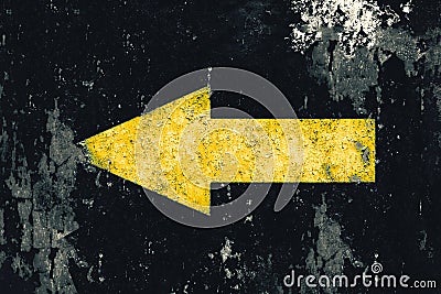 Yellow arrow painted on old grunge and weathered black wall texture background Stock Photo