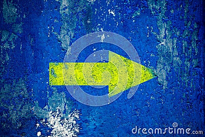 Yellow arrow painted on old grunge and weathered blue wall texture background Stock Photo