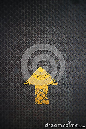 Yellow arrow painted pointing up on steel checkered plate Stock Photo