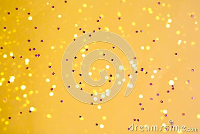 Yellow background with purple stars and glitter spangles. Stock Photo