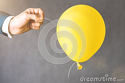 yellow balloon. Man hold needle directed to air balloon. Stock Photo