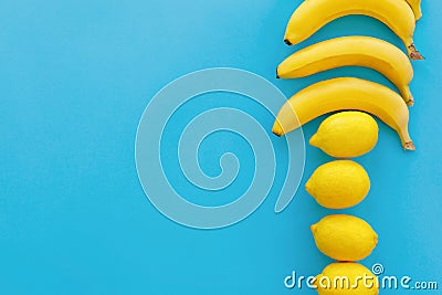 Yellow bananas and lemons on bright blue paper, trendy flat lay. Stock Photo