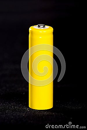 A yellow battery close-up on a dark black blurred background. Electrics. Battery power. Accumulator on the fabric with villi. Stock Photo
