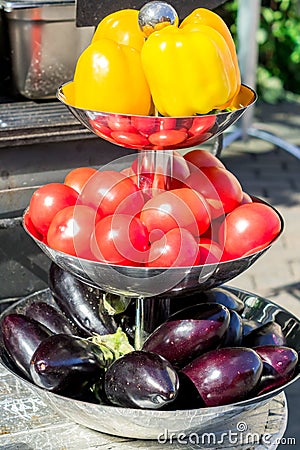 Yellow bell peppers, red tomatoes and purple eggplants on metal three metal bowl outdoors Stock Photo