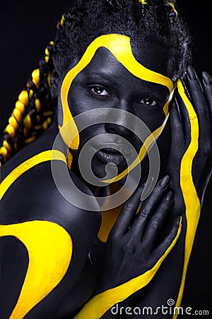 Yellow and black body paint. Woman with face art. Young girl with bodypaint. An amazing model with makeup. Stock Photo