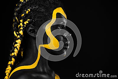 Yellow and black body paint. Woman with face art. Young girl with colorful bodypaint. An amazing afro american model Stock Photo