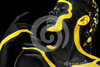Yellow and black body paint. Woman with face art. Young girl with colorful bodypaint. An amazing afro american model Stock Photo